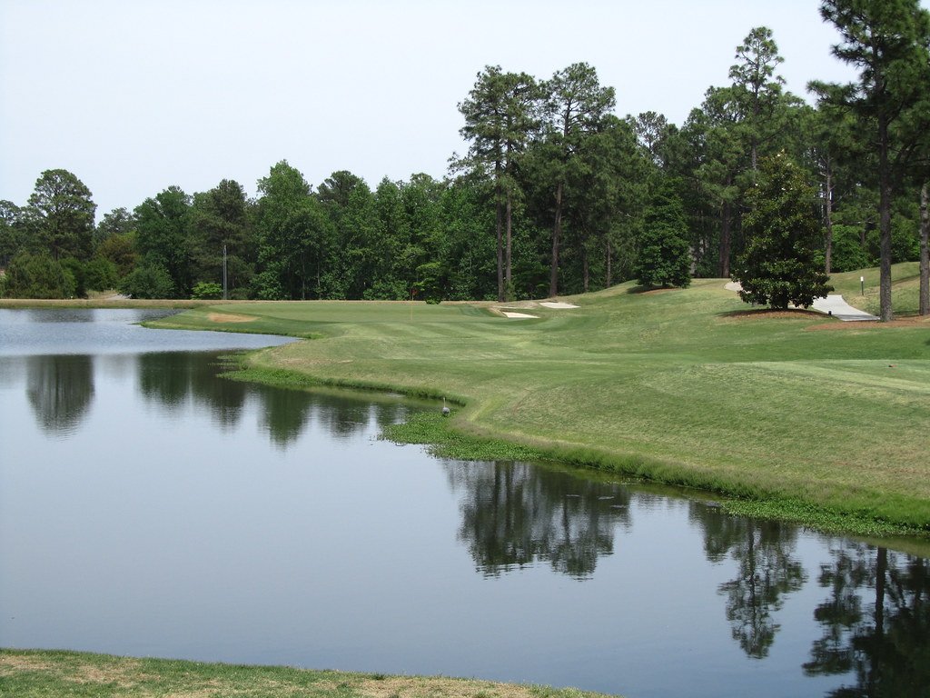 Campo de golf verde con lago y reflejo del agua